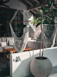 A serene spot at Vayu Retreat Villas during golden hour, featuring a cozy hammock chair and lush plant against the backdrop of a stylish outdoor lounge area. This tranquil scene embodies the luxury and comfort of one of the best hotels in Uvita, Costa Rica, offering a perfect escape in a jungle paradise.