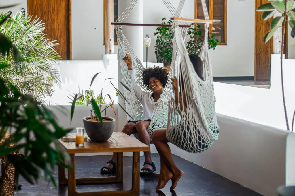 Two people relax in hammock chairs at Vayu Retreat Villas, surrounded by lush plants and a wooden coffee table. This cozy scene captures the laid-back ambiance of one of the best hotels in Uvita, Costa Rica, perfect for a serene jungle retreat.