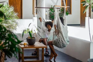 Two people relax in hammock chairs at Vayu Retreat Villas, surrounded by lush plants and a wooden coffee table. This cozy scene captures the laid-back ambiance of one of the best hotels in Uvita, Costa Rica, perfect for a serene jungle retreat.