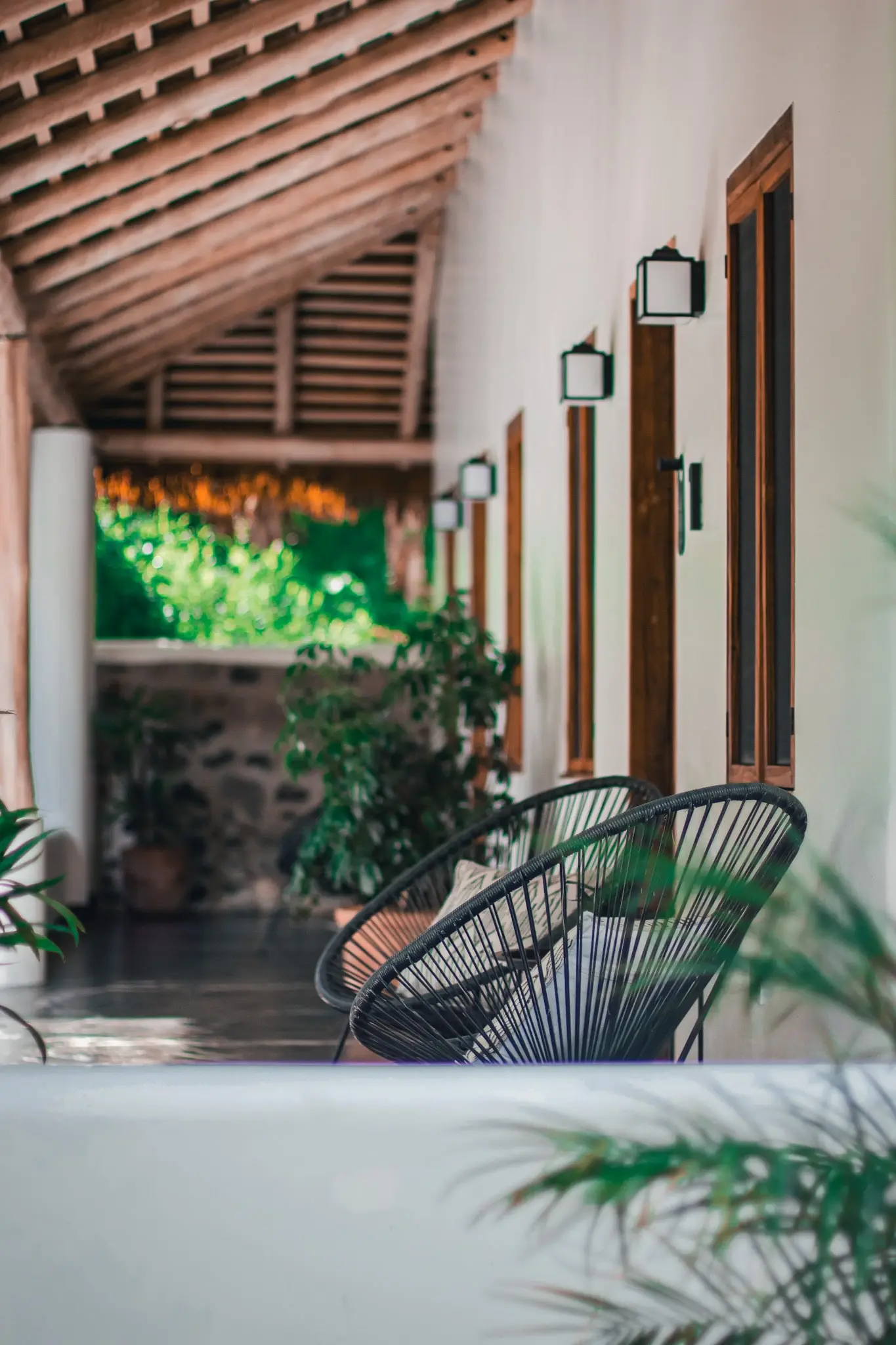 A tranquil corridor at Vayu Retreat Villas, featuring modern black chairs and lush greenery outside the suite doors. This serene setting highlights the luxurious ambiance of one of the best hotels in Uvita, Costa Rica, providing a peaceful and stylish jungle retreat for guests.