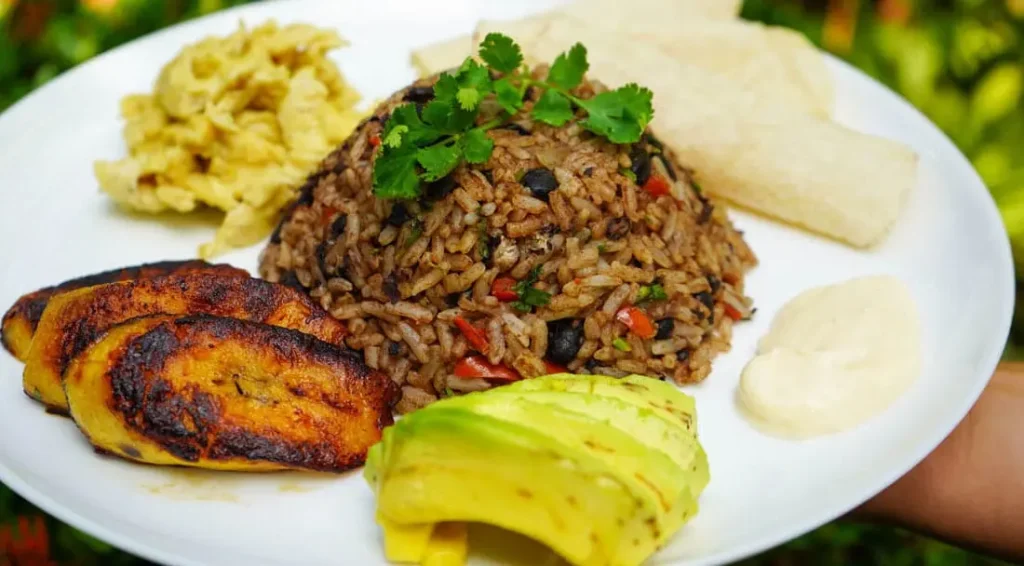A traditional Costa Rican gallo pinto dish served at a soda restaurant Costa Rica, featuring rice and beans, a sunny-side-up egg, grilled plantains, and fresh lime wedges