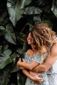 Couple embracing in a romantic moment surrounded by lush tropical leaves, capturing the essence of an all-inclusive Costa Rica honeymoon at Vayu Retreat Villas 