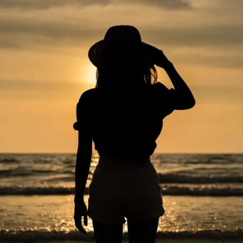 Silhouette of a female solo traveler enjoying a sunset on a beach in Costa Rica. Perfect destination for solo travel and wellness retreats