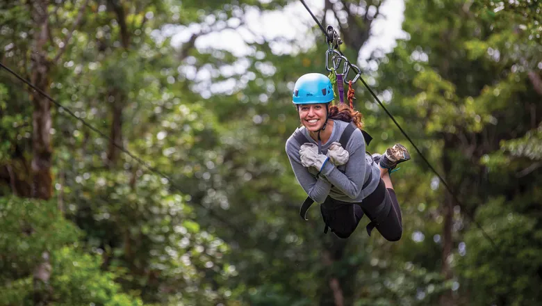 Woman ziplining through the forest in Costa Rica. An exciting activity for solo travelers seeking adventure and safety at Vayu Retreat Villas