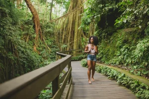 Female solo traveler walking on a wooden pathway through lush jungle in Costa Rica. Ideal for adventure and wellness at Vayu Retreat Villas.