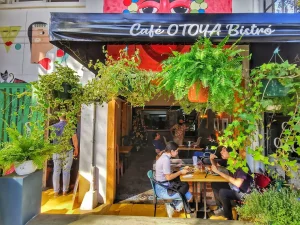 Visiting San José, Costa Rica: The welcoming entrance of Café Otoya, adorned with lush greenery and vibrant decor, perfect for a morning coffee.