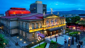 "Visiting San José, Costa Rica: A stunning view of the illuminated National Theater (Teatro Nacional) at dusk, showcasing its neoclassical architecture and vibrant urban surroundings."