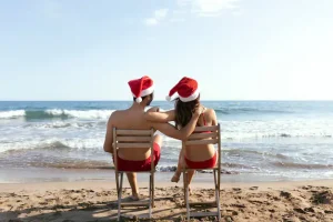 A couple in Santa hats enjoying a beachside Christmas in Costa Rica, with ocean views perfect for a holiday getaway at Vayu Retreat Villas