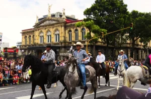 Traditional Tope Nacional parade during Christmas in Costa Rica, with riders on horses passing the historic National Theater in San José.